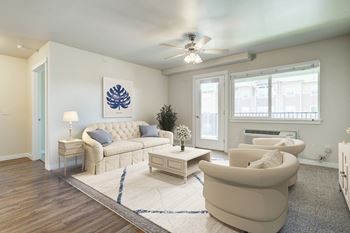 A living room with white furniture and a ceiling fan